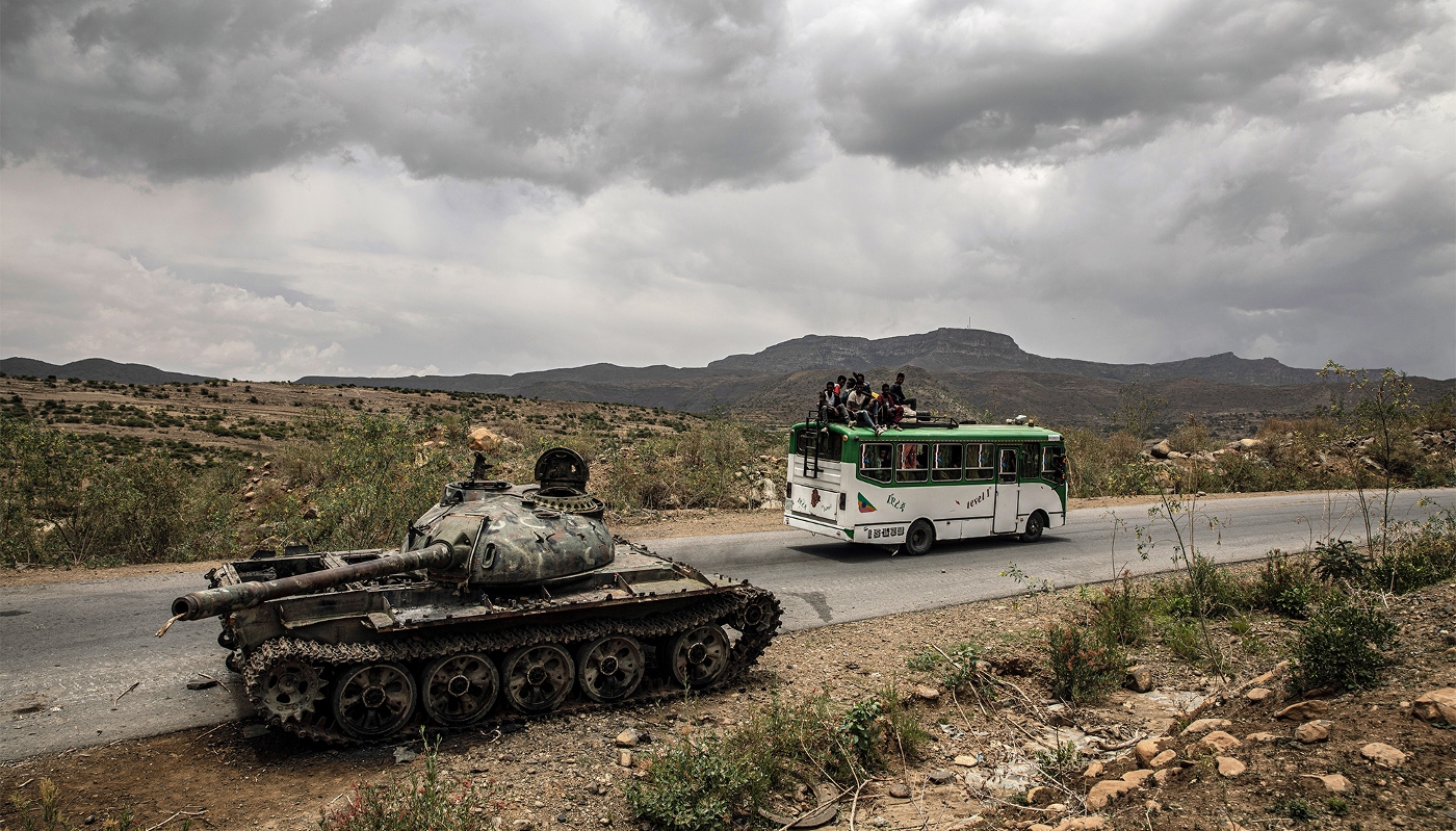 Un bus transportant des civils passe devant un char d'assaut détruit à l'extérieur de Mekele, dans la région éthiopienne du Tigré, en juin 2021.